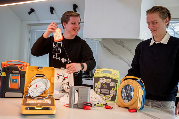 Stef Hordijk (links) en Pepijn Rovers aan de keukentafel met diverse soorten AED's.