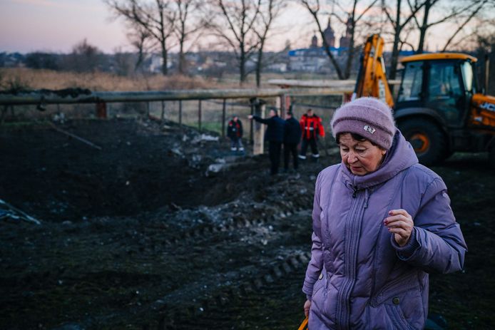 Een vrouw loopt langs een krater achtergelaten door een Russische raketaanval.