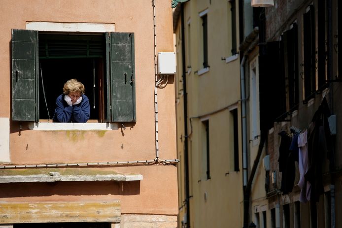 Een vrouw kijkt uit het raam in Venetië, Italië dat ook in lockdown is.