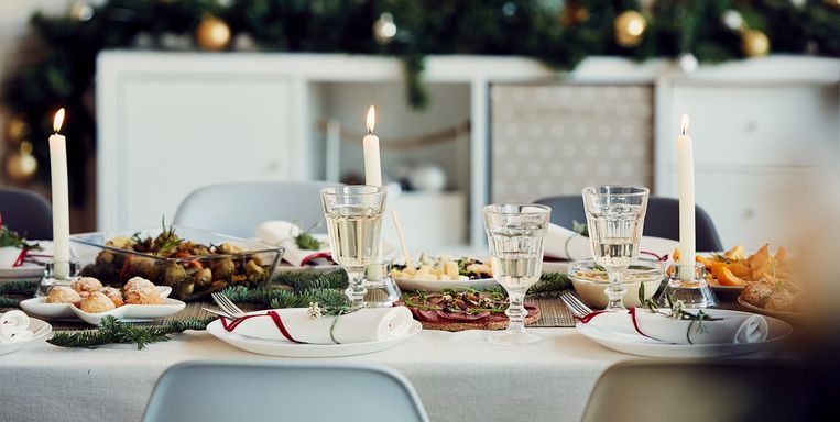 Background image of beautiful table setting for Christmas party with fir elegant candles and delicious homemade food, copy space Beeld Getty Images/iStockphoto