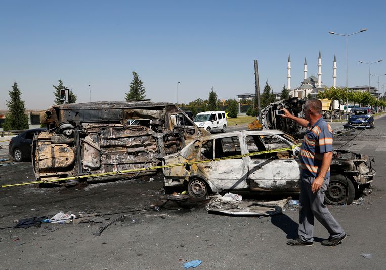 Een man neemt zondag foto's van door een luchtaanval verwoeste voertuigen van burgers en militairen nabij het presidentiële paleis in Ankara. Beeld ap