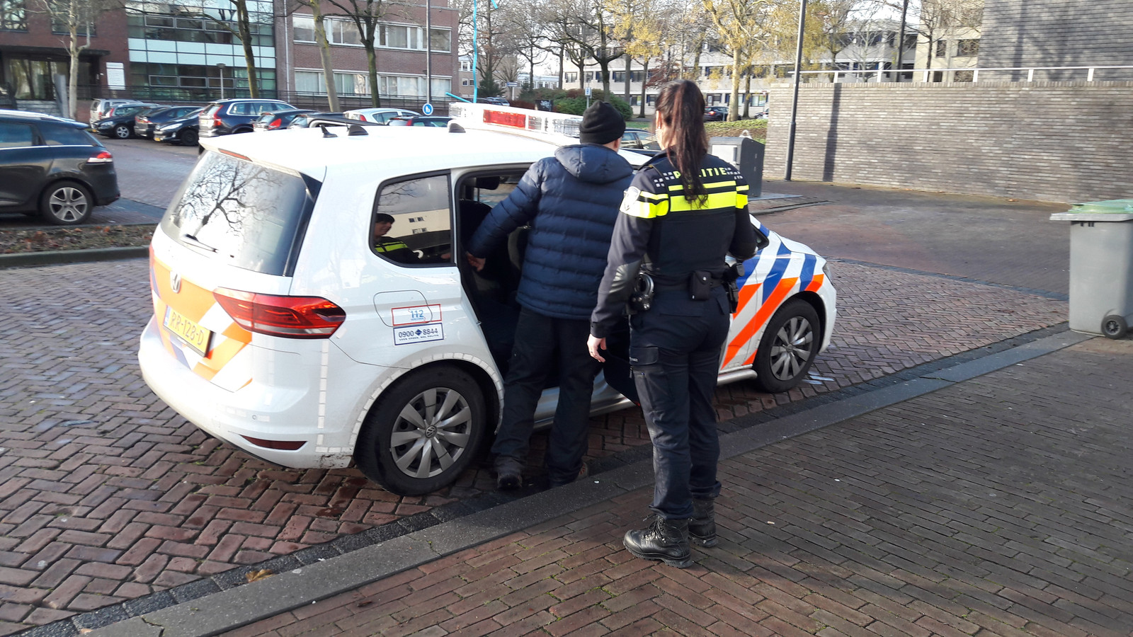 Arie den Dekker wordt door de politie weggevoerd van het Osse gemeentehuis.