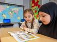 Anastasiia (l, 10) uit Oekraïne en Aisha uit Afghanistan (9) oefenen samen met lezen.