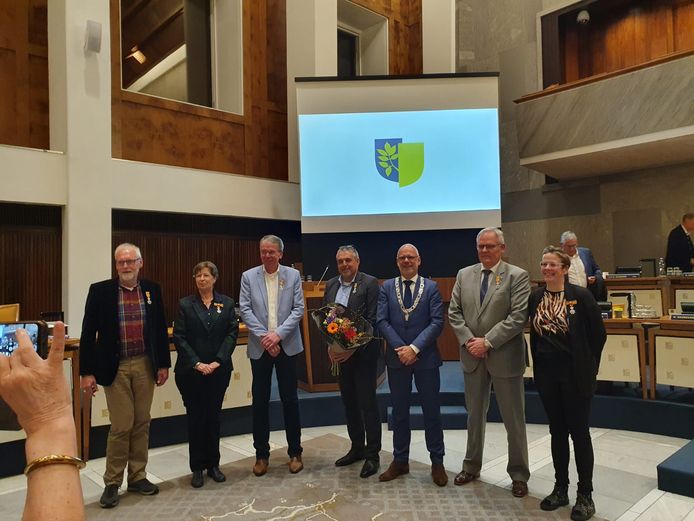 Burgemeester Carol van Eert (derde van rechts) reikte dinsdagavond een koninklijke onderscheiding aan zes vertrekkende raadsleden.