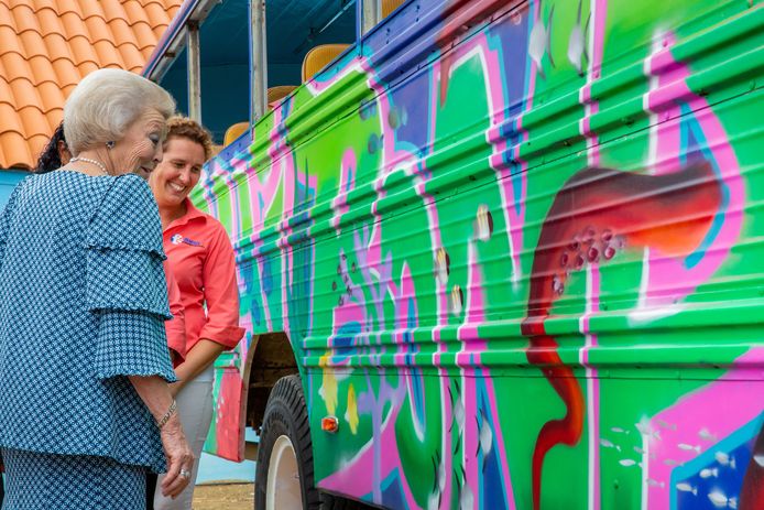 Prinses Beatrix bekijkt een ‘muur’-schildering van jongeren op een toeristenbus.