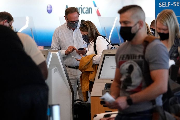Mensen staan met mondkapjes op bij een zelf check-in van American Airlines. Archiefbeeld.