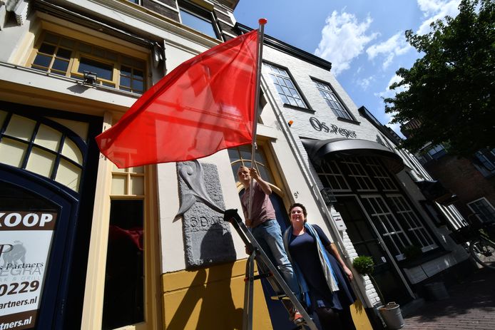 Voorzitter van de jongerentak Jesse Koops (met vlag) en landelijk PvdA-voorzitter Nelleke Vedelaar voor het gebouw in Zwolle waar de SDAP 125 jaar geleden werd opgericht.