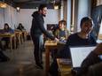 Steeds meer mensen komen in een koffiezaak werken op hun laptop.