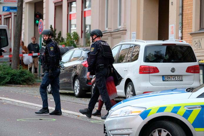 Leden van een speciale politie-eenheid lopen langs een kogelhuls terwijl ze een vrouw uit het afgezette gebied begeleiden.