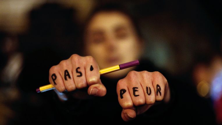 'Pas peur' (geen schrik) staat er te lezen op de handen van deze demonstrante in Parijs. Beeld AP
