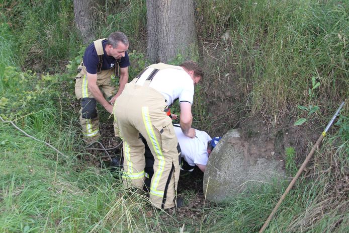 Brandweerlieden uit Enter zijn bezig een kat uit een rioolbuis te bevrijden.