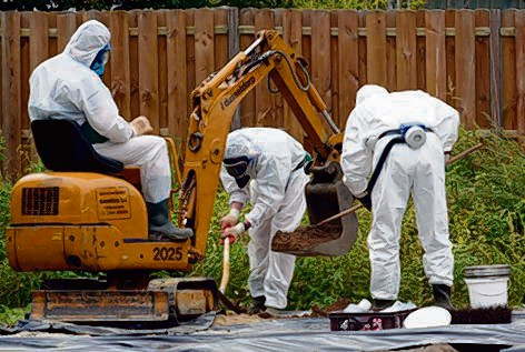 Mannen in witte pakken zijn bezig met asbestsanering in de Goorse wijk De Hogenkamp.