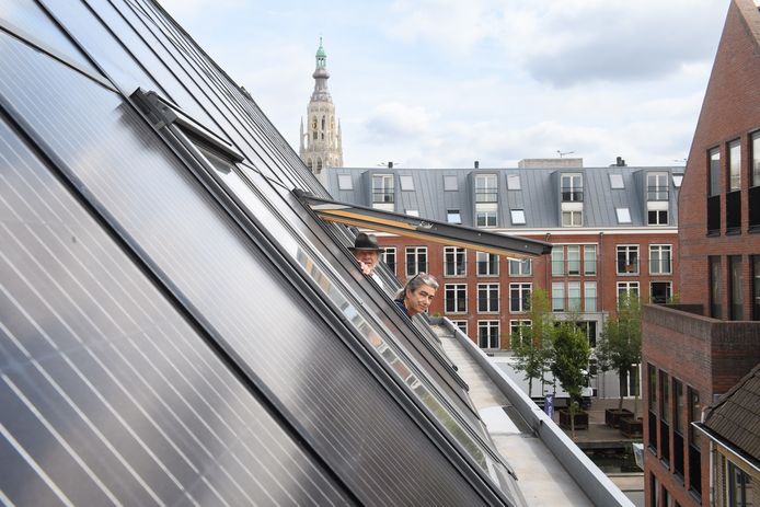 Conita Vermeulen kijkt samen met Eloi Koreman uit een van de ramen tussen de panelen op het pand in Breda.