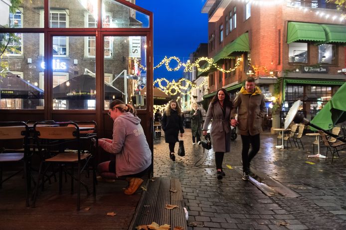Avondlockdown om 17.00 uur in Breda. Bij café Sam Sam op de Grote Markt worden de terrasstoelen vastgemaakt terwijl het winkelend publiek naar huis gaat.