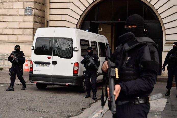 De politiewagen met Jawad Bendaoud arriveert bij de rechtbank in Parij. Zwaarbewapende antiterrreureenheden bewaken het rechtsgebouw.